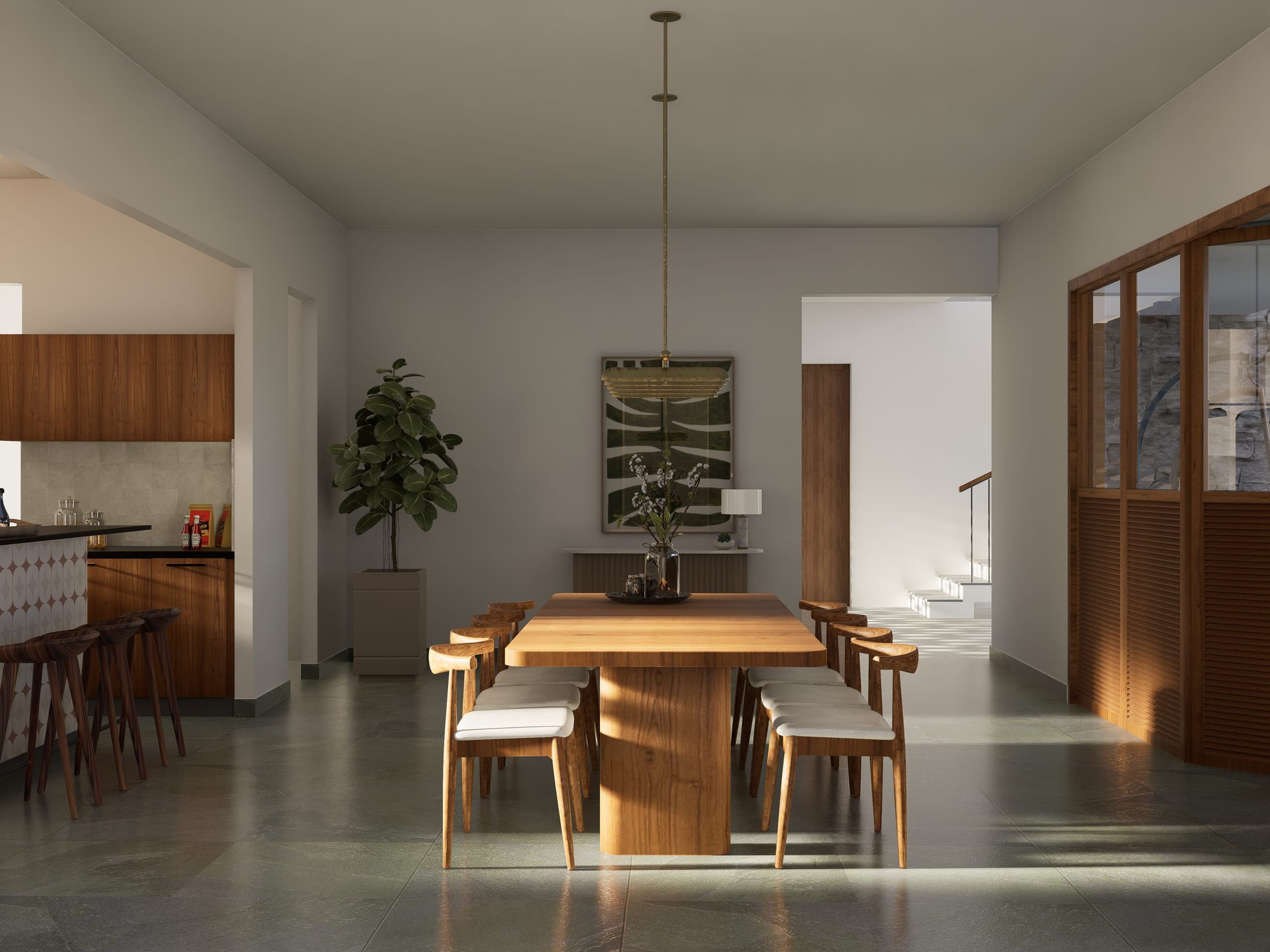 A solid timber dining table anchors the ground floor, opening directly onto the courtyard step-out beyond. From there, the view extends outward across the plantation, layering interior, threshold, and landscape in a single unbroken sequence.