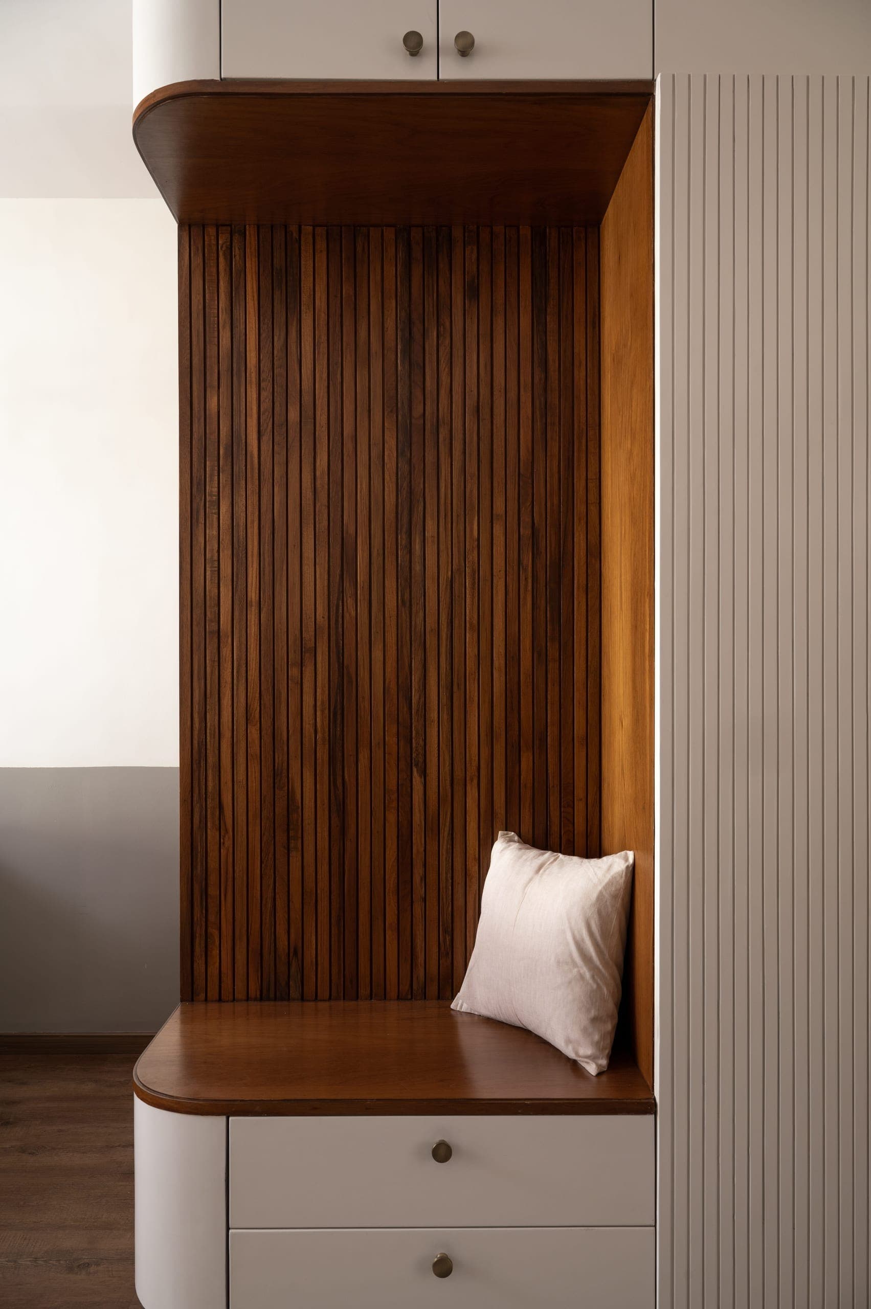 Woodwork boasts textured grooves and rounded edges for safety. Sage green furniture complements the neutrals, creating a subtle connection to the lush greenery outdoor. Strategically placed teak grab bars blend seamlessly, aiding navigation.