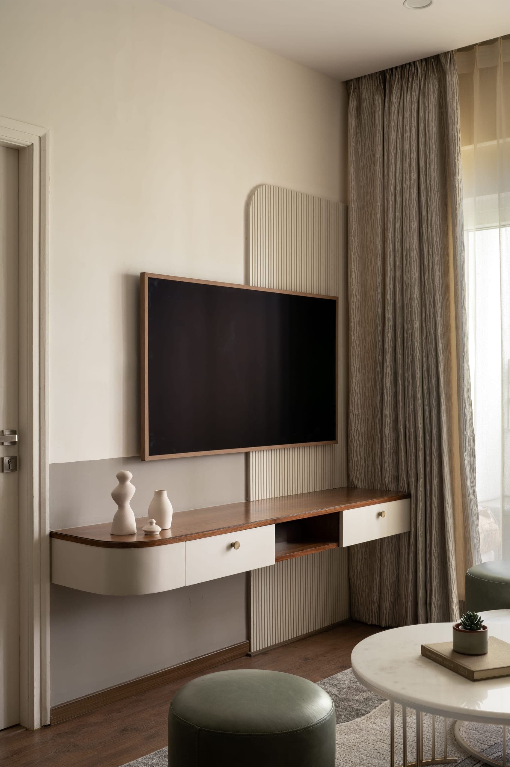 The apartment is finished in a warm white, neutral palette that keeps spaces open and well-lit. A muted taupe half-wall adds depth without compromising volume.