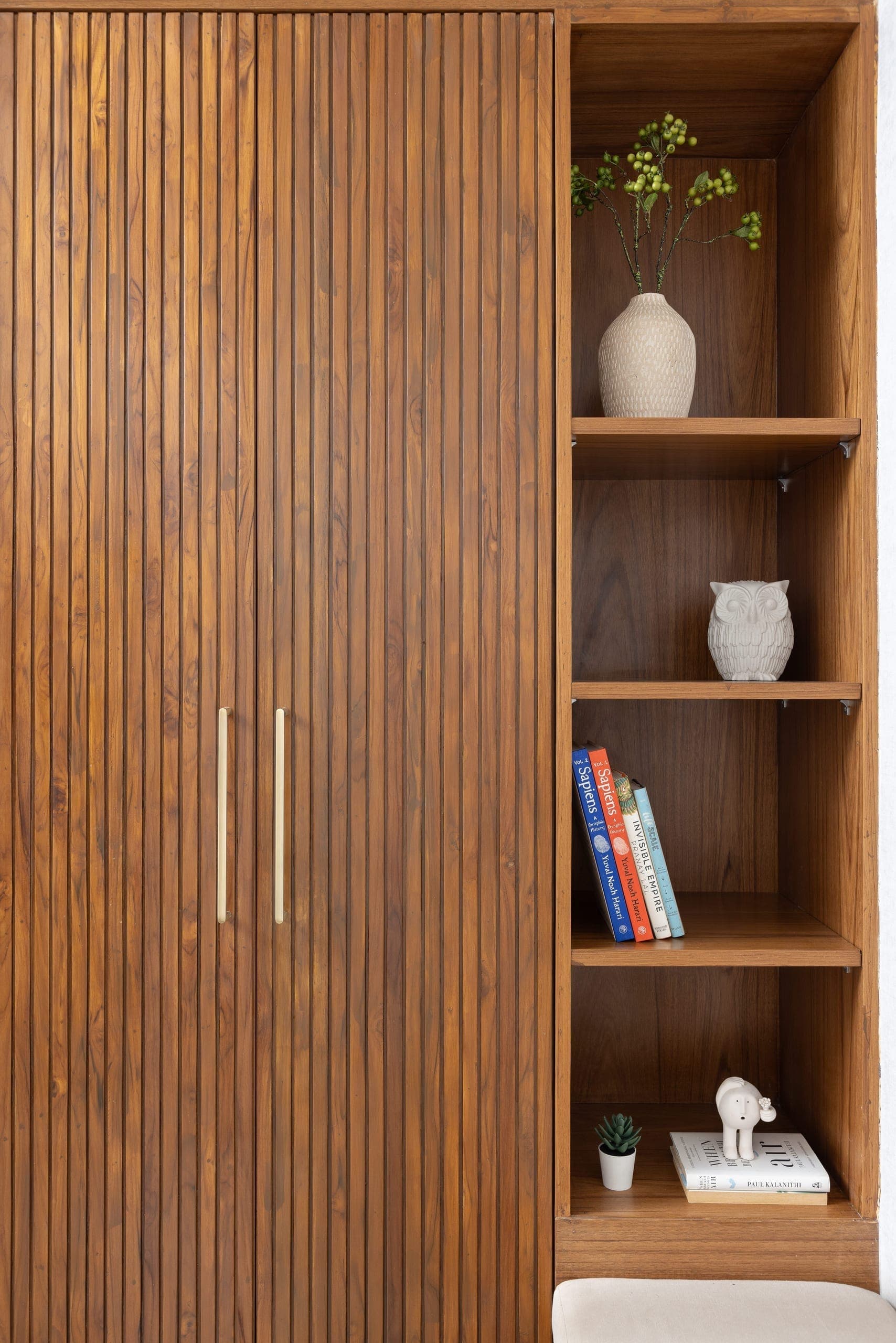 The entry was reworked to create a functional foyer from an underutilised utility space. Teak-shutter storage, open shelves, and a floating bench bring clarity, utility, and ease to the transition into the home.